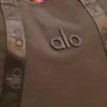 نمای نزدیک لوگوی برجسته ALO روی ساک ورزشی قهوه‌ای کد 520